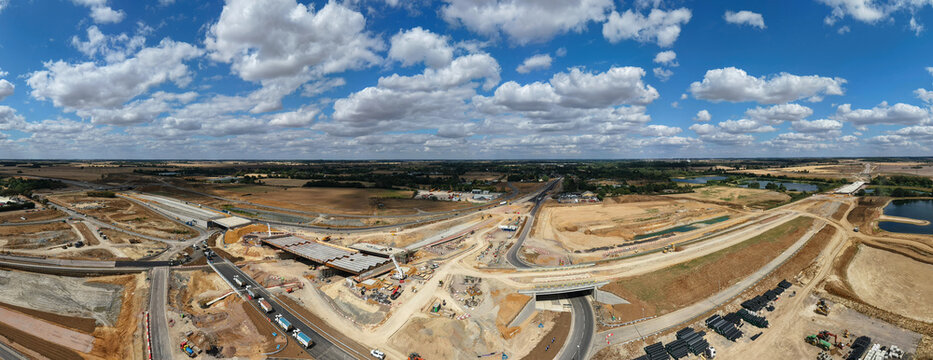 Aerial view of Black Cat Roundabout highway construction showing civil engineering works, new road infrastructure, heavy machinery, and rural landscape in Chawston, England, United Kingdom.