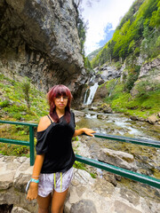 Fototapeta premium a girl t looks at a waterfall, happy young traveling