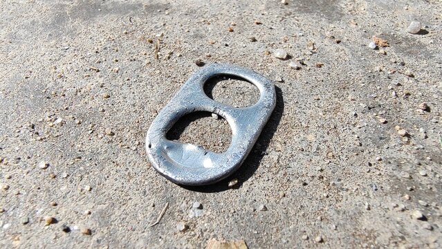 Discarded Aluminum Can Pull Tab on Concrete Surface