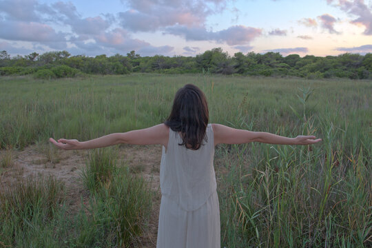 Free young woman with arms outstretched standing in a wild field