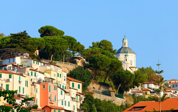 Colorful houses on a hillside with umbrella pines and a baroque church dome , Sanremo, Liguria, Italian Riviera, Italy