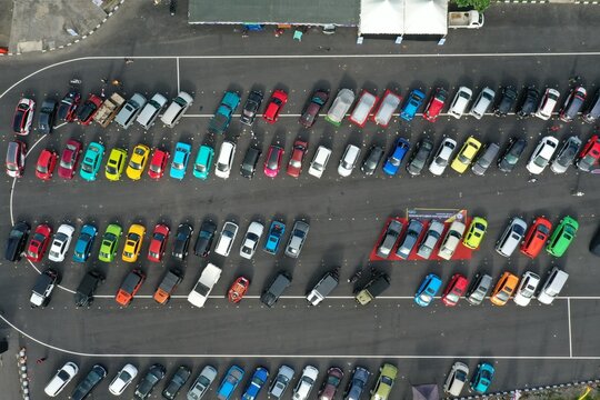Aerial view of Maguwoharjo stadium parking lot filled with many colorful cars parked in orderly rows in Depok, Special Region of Yog, Indonesia.