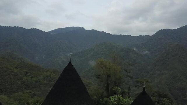 Drone video of isolated Wae Rebo village nestled in lush tropical mountain valley