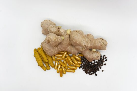 ra&iacute;z de jengibre fresca, trozos de ra&iacute;z de c&uacute;rcuma, granos de pimienta negra y c&aacute;psulas de suplementos diet&eacute;ticos que combinan estos tres ingredientes herbales