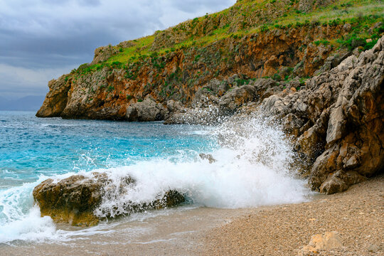 Powerful ocean dramatic turquoise water waves splashes rocky cliffs on a scenic Mediterranean coastline
