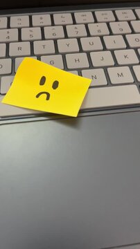 Sad face sticky note on laptop keyboard job dissatisfaction