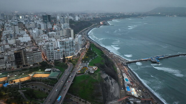 Aerial view of Love Park situated on the coastal cliffs overlooking the Pacific Ocean with the urban skyline and highway in Miraflores, Provincia de Lima, Peru.