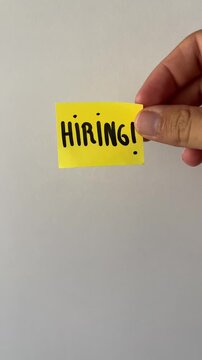 Hand holding hiring sticky note on white background
