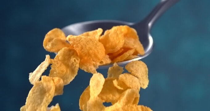 Corn flakes falling from a spoon in slow motion on blue background
