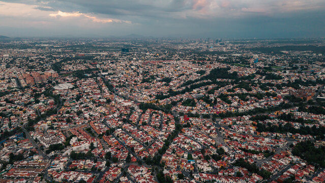 Aerial view of the dense residential urban landscape with winding streets and rooftops under a cloudy sky in Ciudad Lopez Mateos, Estado de Mexico, Mexico.
