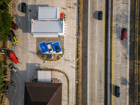 Aerial view of a highway rest area in Salatiga, featuring a parking spaces, electric vehicle charging stations, and a multi-lane highway in Salatiga, Central Java, Indonesia.