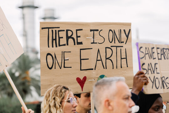 Climate activists holding handmade signs advocating for global environmental protection and sustainability during a public demonstration against industrial emissions and global warming concerns