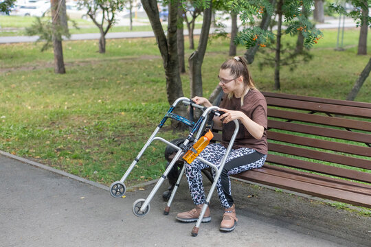 A Caucasian woman with cerebral palsy sits on a park bench.