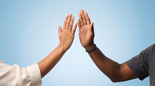 Two diverse hands high-fiving against a soft blue background celebrating success