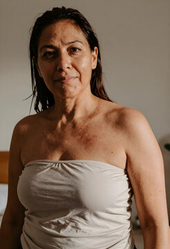 Self acceptance and body positivity, mature woman with natural skin texture and authentic beauty looking at camera in a candid indoor portrait