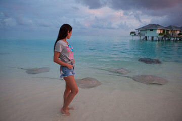Woman walking among stingrays in the shallow water of Maldives © Viacheslav Zhukov