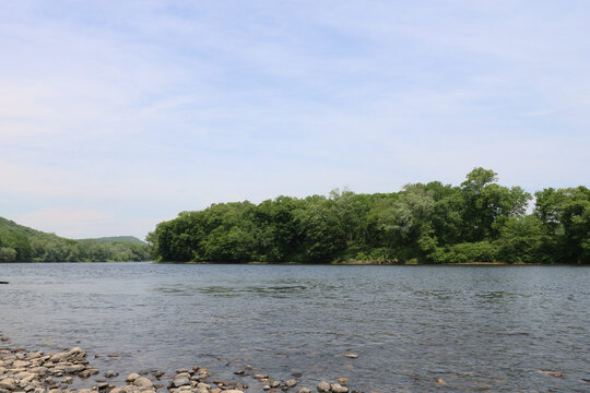 Stone strewn shore reaching down a summer river