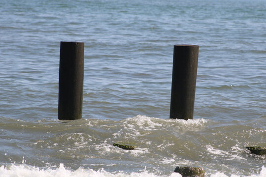 Two barnacled pilings rising from the surf