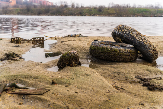 View of discarded tires and debris on the sandy shore of Lake Varna, Varna, Bulgaria.