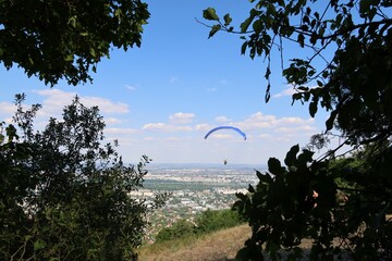 A paraglider flies over the northern part of Budapest as seen from the forest. © Zutty