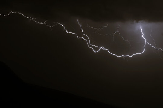 M&uacute;ltiples rayos y descargas el&eacute;ctricas ramificadas cruzando el cielo nocturno nublado durante una tormenta.