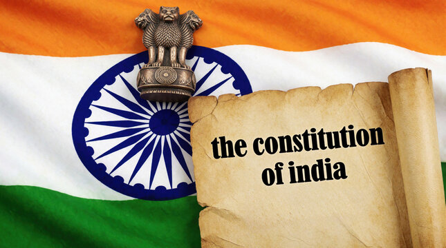 Indian Constitution Preamble scroll over national tricolor flag. Ashoka Chakra emblem, State Emblem of India symbol displayed. Text reads constitution of india on old parchment paper. Patriotic