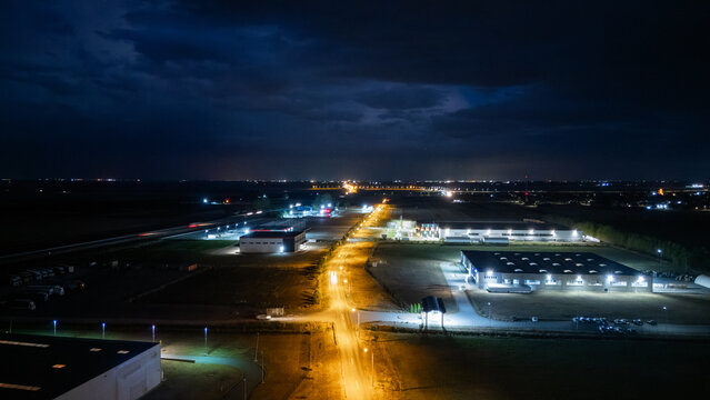 Aerial view of an industrial zone in Sremska Mitrovica at night, featuring illuminated warehouses, street lighting, and a dark sky in Sremska Mitrovica, Vojvodina, Serbia.