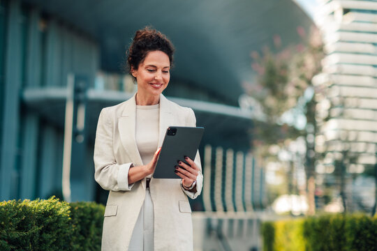 Businesswoman using digital tablet in urban city setting, representing modern communication and professional work life