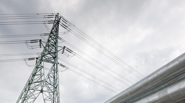 a pipeline and a power transmission tower against a gray sky