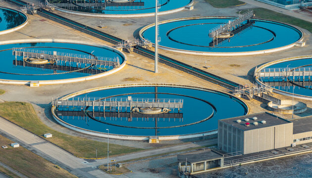 Aerial view of multiple circular clarifiers with rotating bridge systems at a large wastewater treatment facility in Italy.