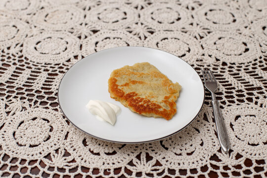 Homemade potato pancake with sour cream on white plate