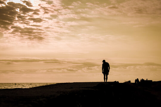 Hombre caminando al borde de un muelle al atardecer
