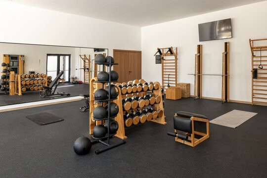 Modern luxury gym interior with wooden dumbbells and fitness equipment