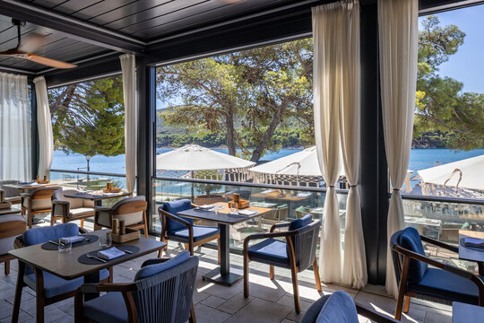 Elegant restaurant terrace with sea view dining tables and curtain decorations