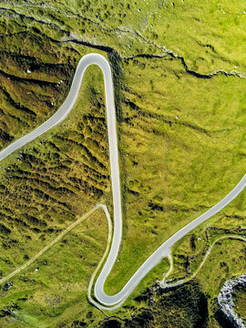 Aerial view of Silvretta-Hochalpenstrasse winding through lush green alpine meadows with sharp hairpin turns Partenen, Vorarlberg, Austria.