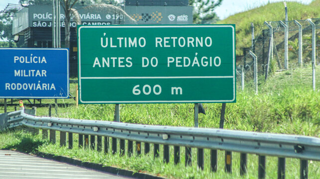 Last return before toll sign at 600 meters beside highway police signage