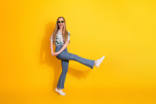 Cheerful young woman wearing fashionable casual attire standing with a joyful pose against a vibrant yellow background