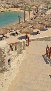 Sunny beachfront scene with stone walkway and straw umbrellas Egypt. Hurghada