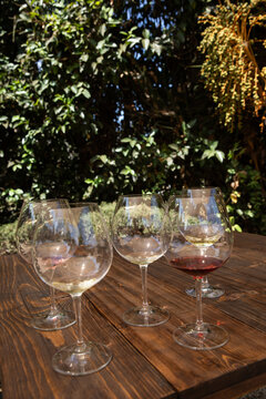 multiple glasses for wine tasting on a wood table outdoors at a winery tasting