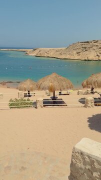Serene beachfront oasis with straw umbrellas and palm trees in idyllic desert landscape Egypt. Hurghada