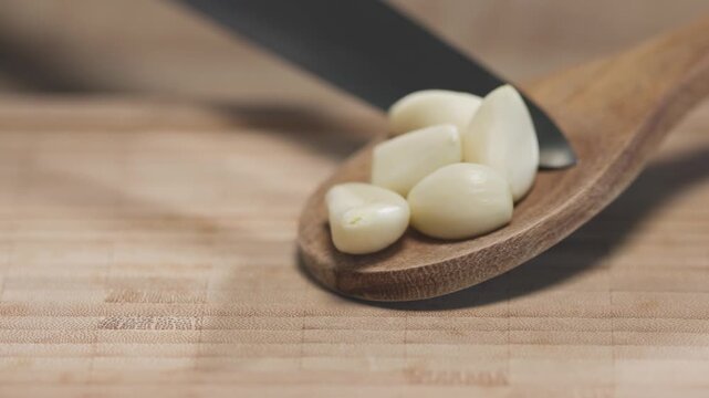 chef places fresh garlic cloves on wooden kitchen table to prepare healthy meal, food closeup. Ingredients for tomato pasta