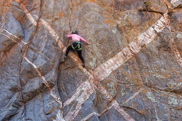 Athletic rock climbers scaling a high vertical crag marked by striking geometric white mineral dykes in an arid canyon landscape. © Valentin
