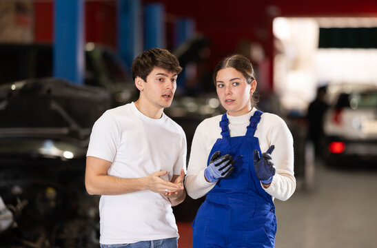 European guy consults with a car service worker about the repair and diagnostics of the car. Female mechanic gives recommendations for changing the oil, filter and checking the engine