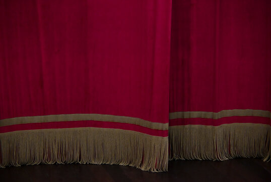 red velvet theater curtain with golden fringe detail, classical stage curtain on wooden floor, elegant performing arts background concept