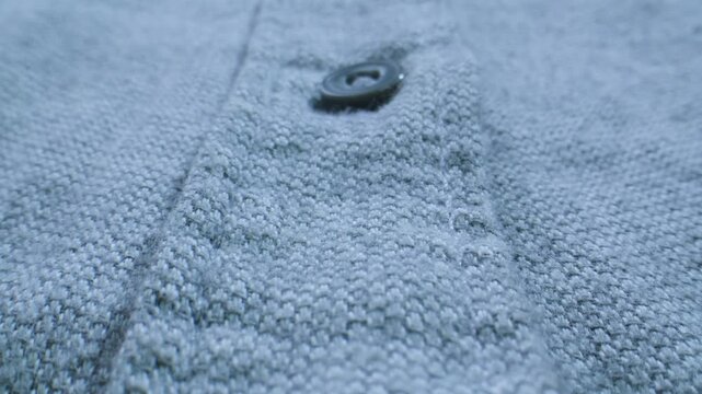 Shirt fabric texture with button, blue grey cotton shirt extreme close up macro, textile detail for garment production, sewing and clothing factory