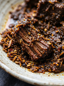 Close up of traditional Indonesian beef rendang served in a ceramic bowl.