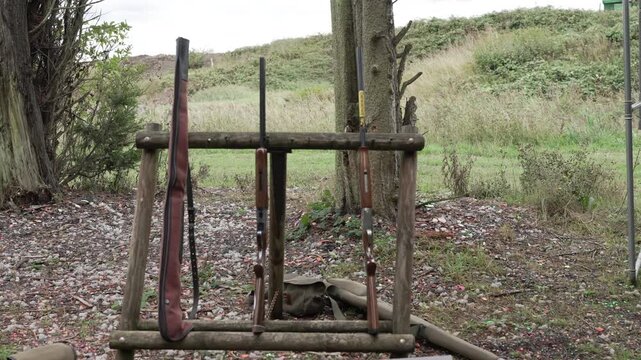 Shotguns resting on wooden stand at outdoor shooting range game hunting