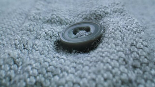 Sweater button on blue wool knit, knitted cardigan texture extreme close up macro, knitwear detail for clothing factory and garment production
