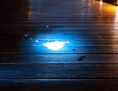 glowing forensic chemical stain on dark wooden floor revealing hidden evidence during investigation