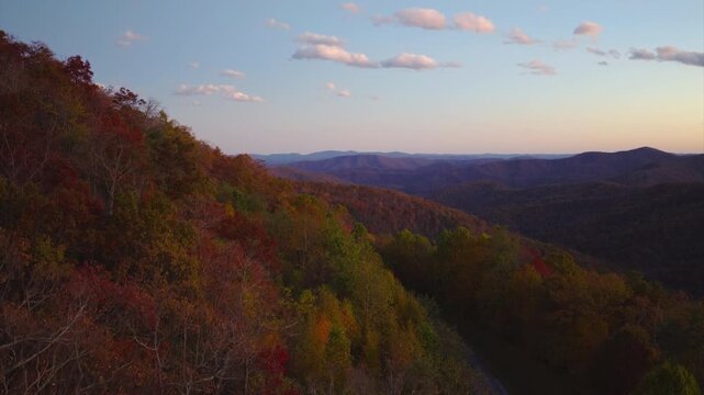 Colorful mountain forest in fall season stretching across rolling hills under nightfall. Vibrant foliage creates picturesque landscape full of seasonal beauty.
